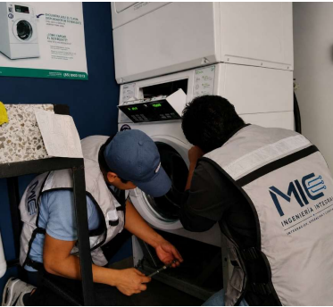 Técnicos de MIC realizando mantenimiento en un equipo de lavandería